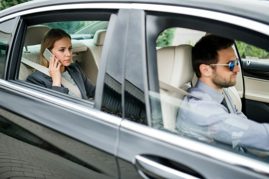 Businesswoman sitting on back seat in taxi car, talking on the phone.