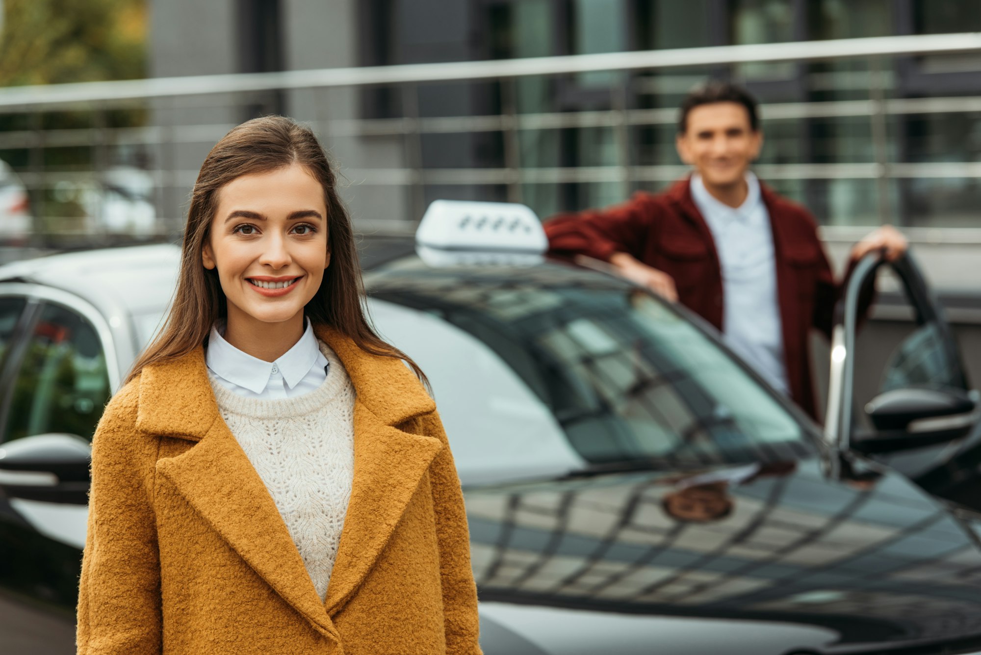 Selective focus of woman smiling at camera and taxi driver at background