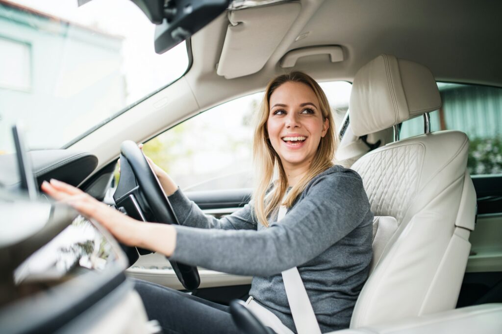 Young woman driver sitting in car, driving.